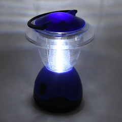 The blue and clear plastic lantern is brightly illuminated, casting a glow on the surrounding gray surface.