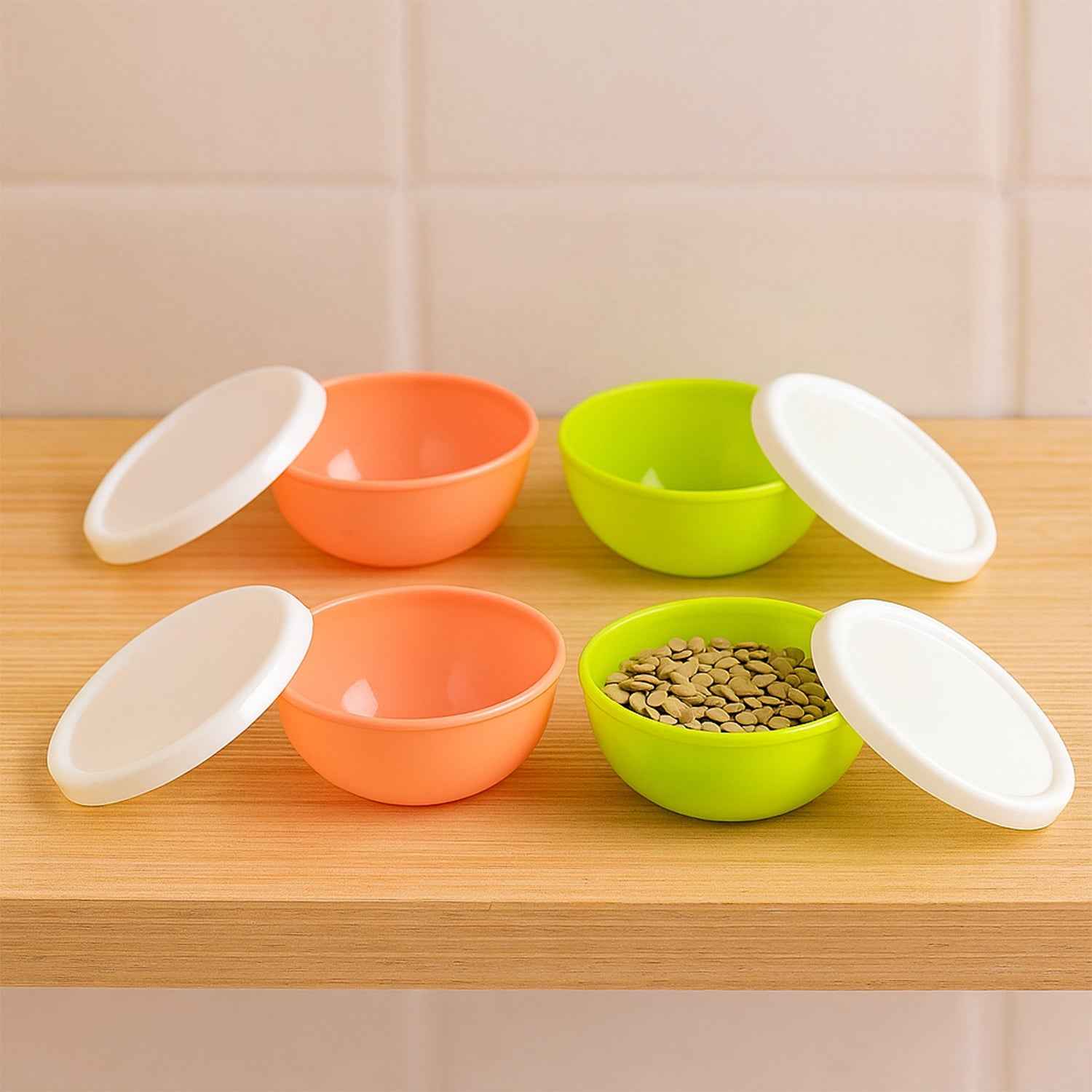 Set of four small round plastic bowls with clear lids for food storage.
