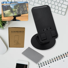 A sleek black rotating mobile stand, folded compactly on a desk, ready for use.