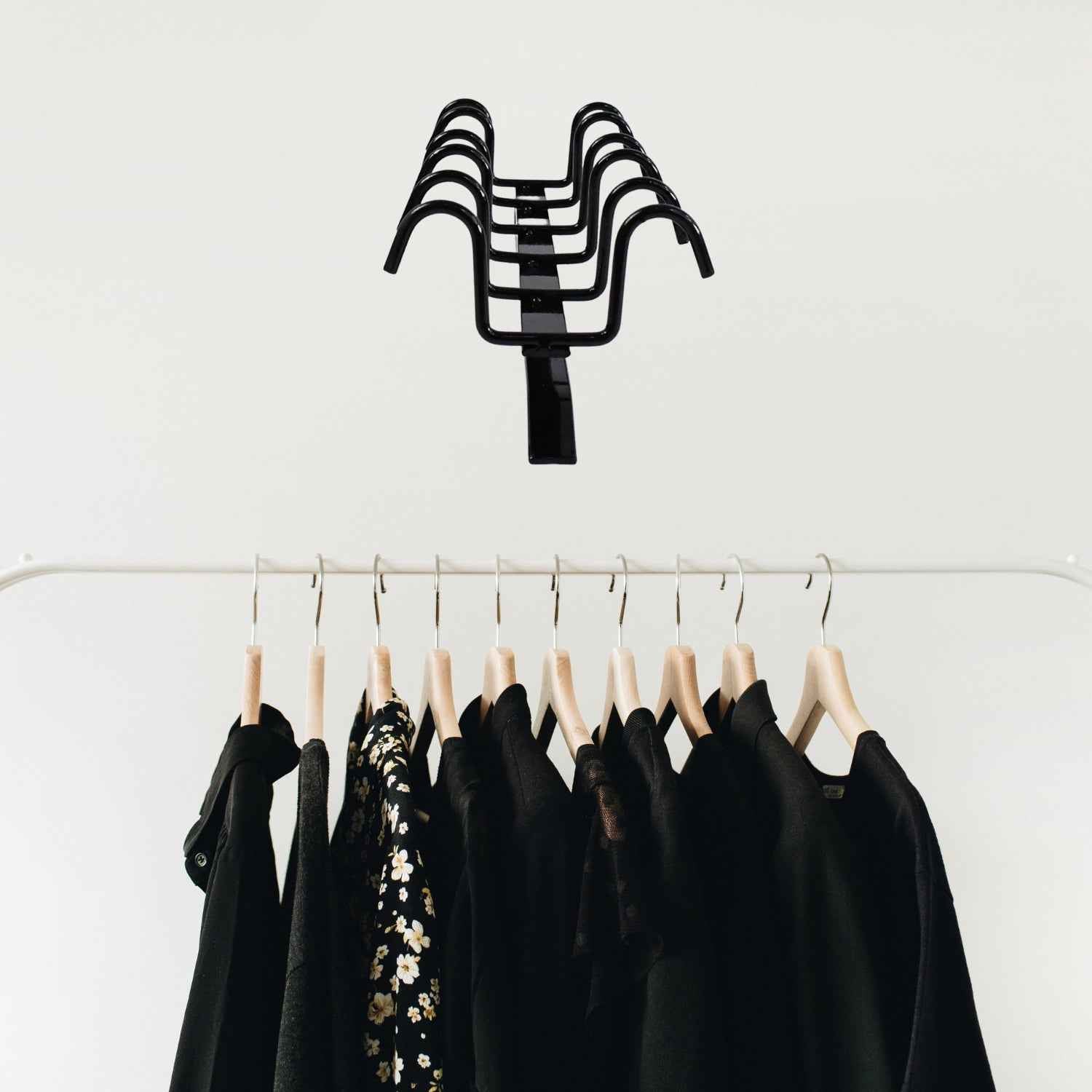 Versatile metal hanger rack holding kitchen utensils and towels.