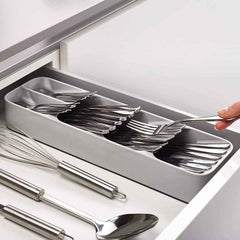 An empty, grey plastic cutlery tray with multiple compartments for kitchen drawer organisation.