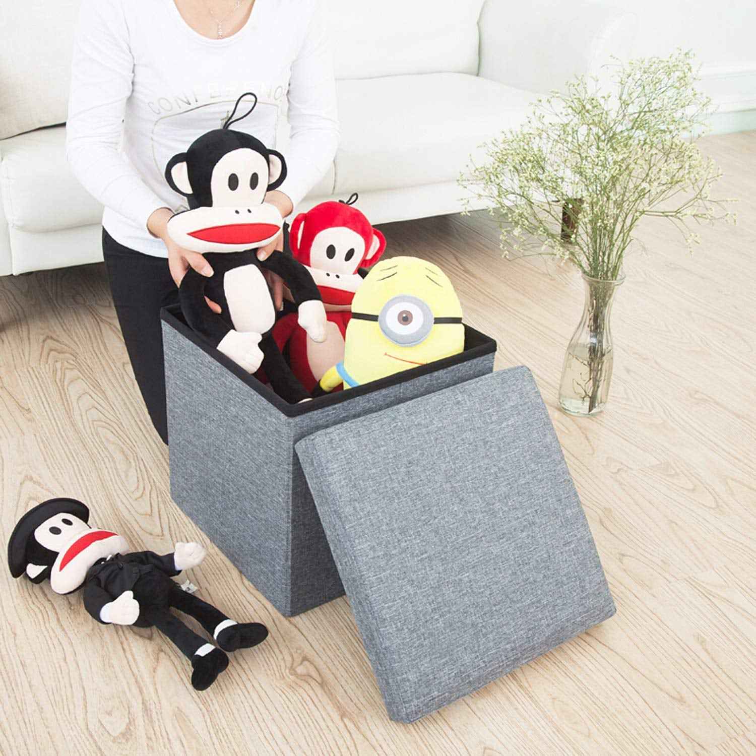 A stylish grey foldable storage stool with a comfortable cushion top, perfect for living room organization.
