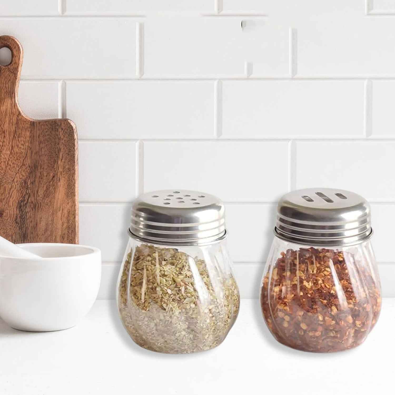 Oregano & Chilli Flakes Dispenser Set with clear plastic body and stainless steel lids on kitchen counter