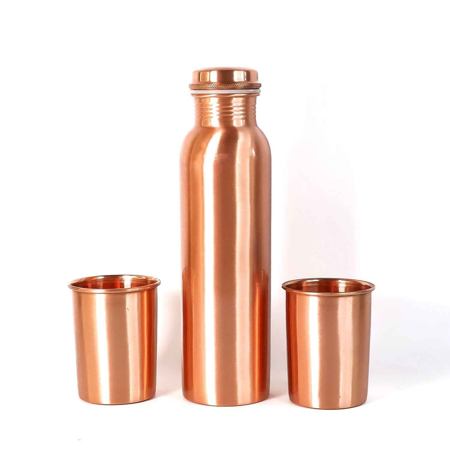 A person pouring water from the leakproof copper bottle into one of the matching glasses.