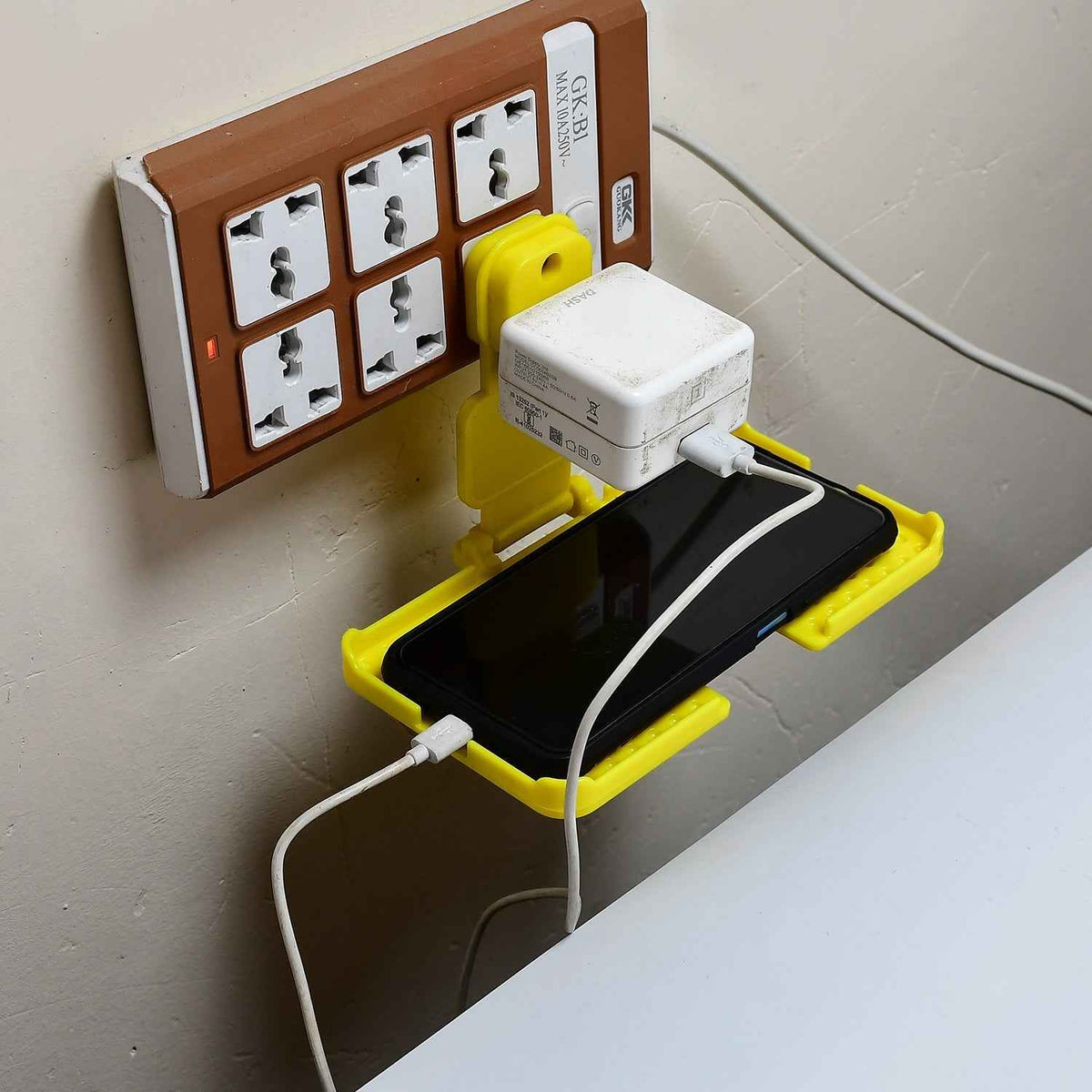 Yellow Mobile Charging Wall Holder securely plugged into a power socket.