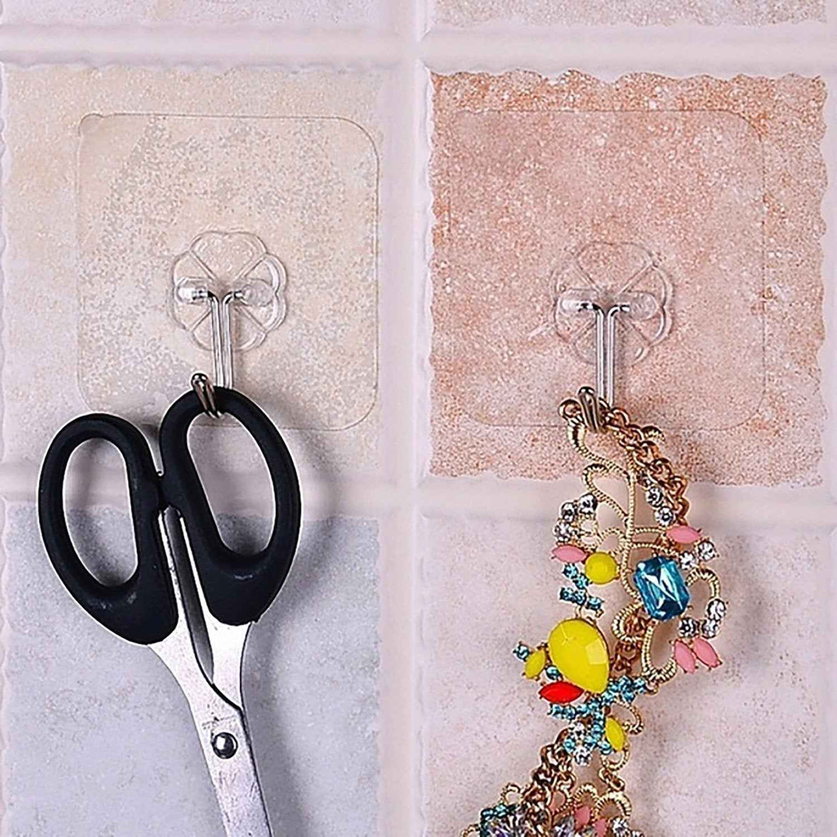 Pair of small stainless steel adhesive hooks on a white wall.