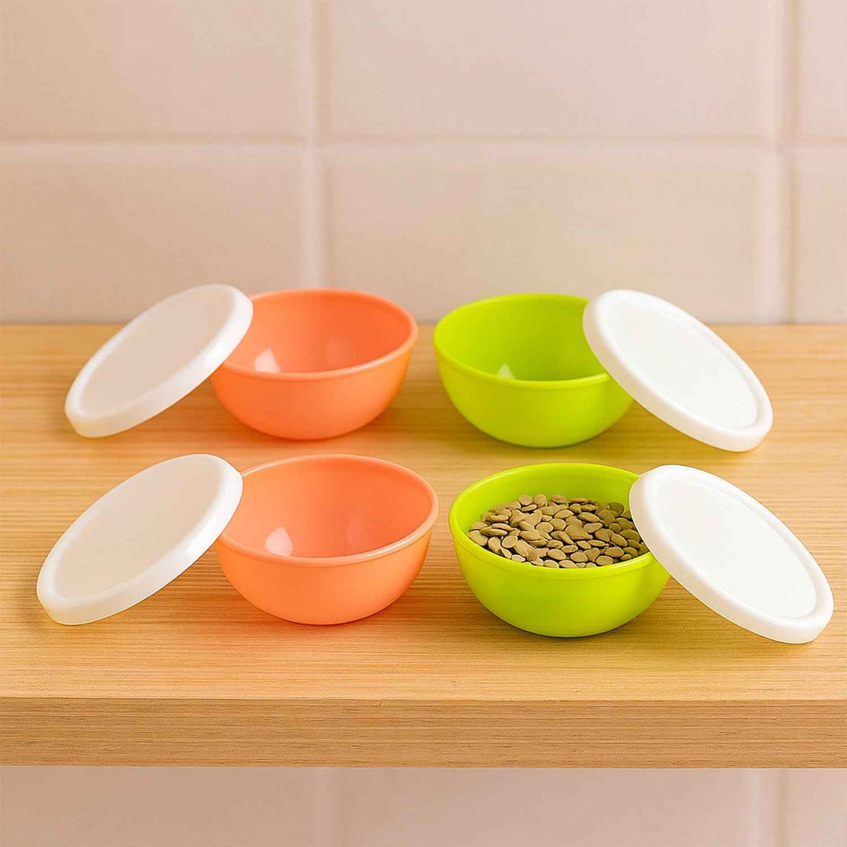 Set of four small round plastic bowls with clear lids for food storage.