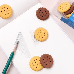 A child's hand holding a fun biscuit eraser next to a pencil, showing usage.